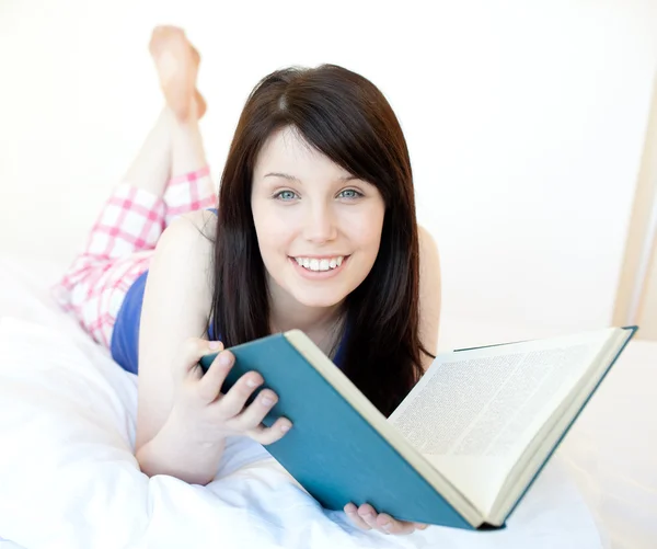 Porträt eines strahlenden Teenie-Mädchens, das auf einem Bett liegend studiert — Stockfoto