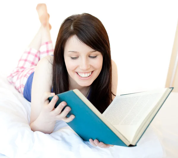 Porträt einer selbstbewussten Teenagerin, die auf einem Bett liegend studiert — Stockfoto