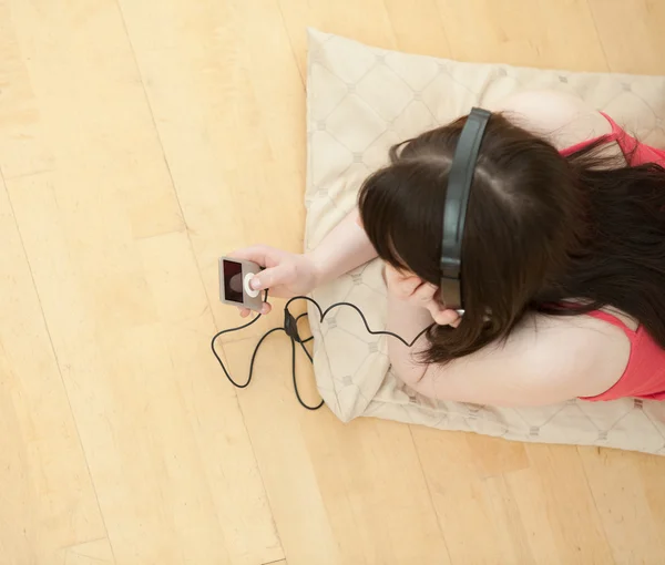 Brunett kvinna lyssnar musik liggande på golvet — Stockfoto