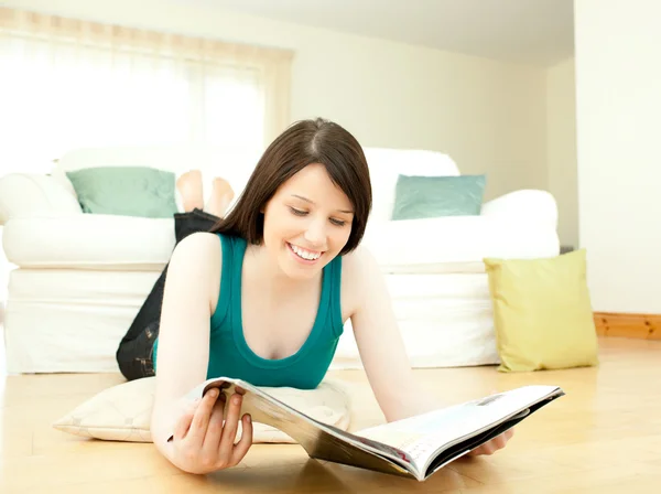 床に横たわって雑誌を読む女性の笑みを浮かべてください。 — ストック写真
