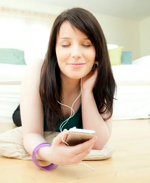 Dromerige vrouw luisteren muziek op de vloer liggen — Stockfoto