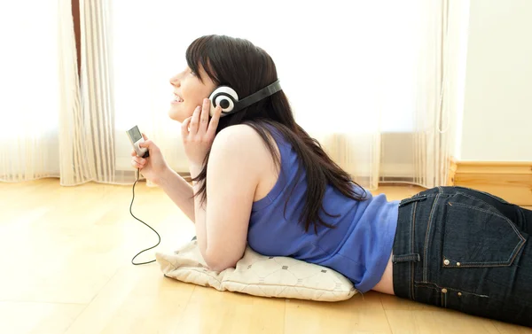Mulher feliz ouvindo música deitada no chão — Fotografia de Stock