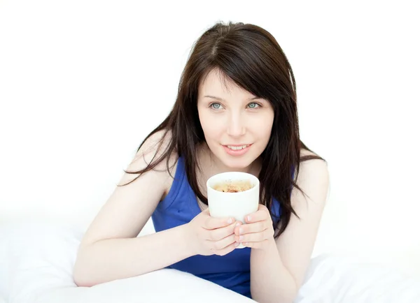 Charming woman drinking a coffee sitting on her bed — Stock Photo, Image