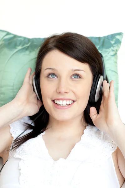 Glad kvinna lyssnar musik liggande på en soffa — Stockfoto