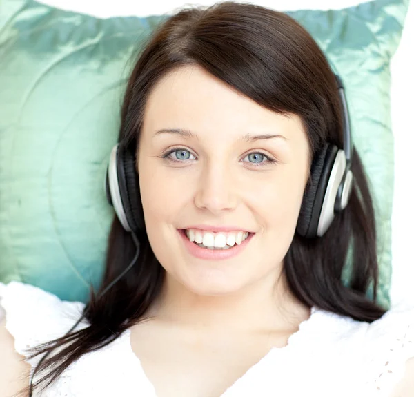 Ung kvinna lyssnar musik liggande på en soffa — Stockfoto