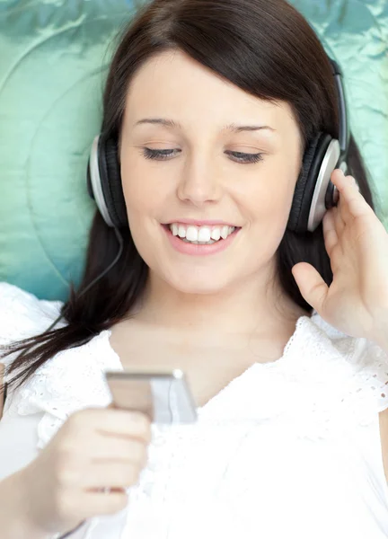 Vacker kvinna lyssnar musik liggande på en soffa — Stockfoto