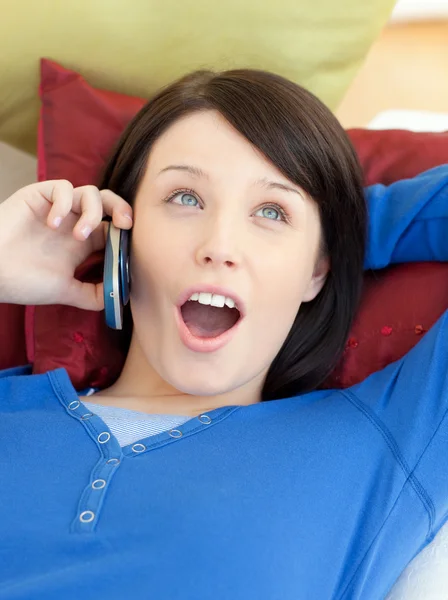 Překvapený mladá žena mluví telefonu ležet na pohovce — Stock fotografie