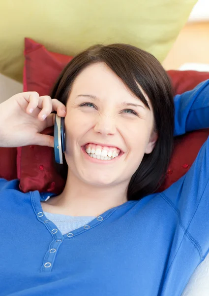 Смеющаяся молодая женщина разговаривает по телефону, лежа на диване — стоковое фото