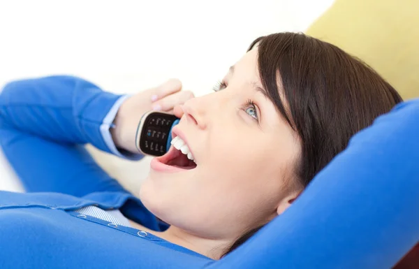 Mujer joven asombrada hablando por teléfono tumbada en un sofá —  Fotos de Stock