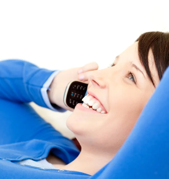 Vrolijke jonge vrouw praten over telefoon liggen op een sofa — Stockfoto