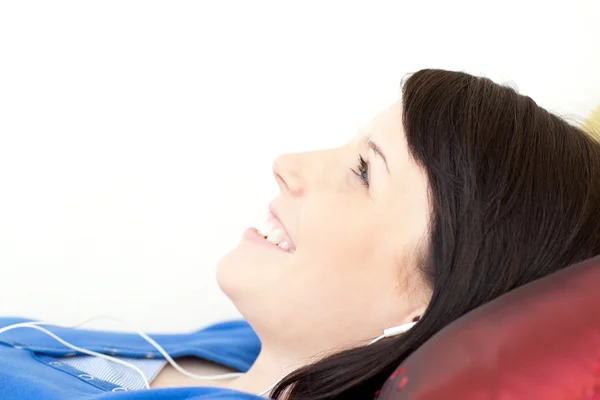 Attractive teen girl listening music lying on a sofa — Stock Photo, Image