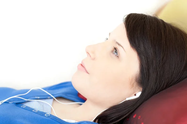 Linda chica adolescente escuchando música tumbada en un sofá —  Fotos de Stock