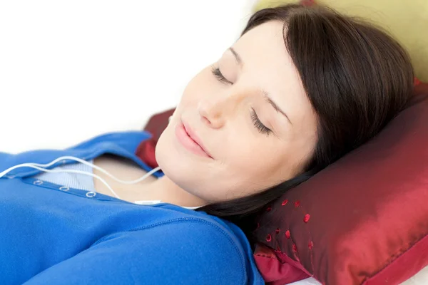 Relaxado jovem mulher ouvindo música deitada em um sofá — Fotografia de Stock