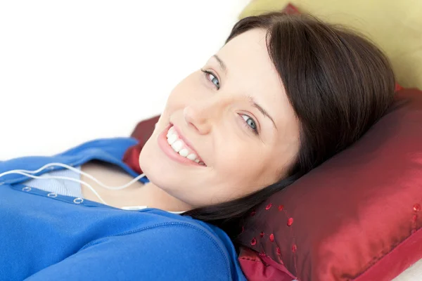 Giovane donna allegra che ascolta musica sdraiata su un divano — Foto Stock