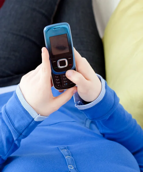 Close-up of a woman sending a text lying on a sofa — Stock Photo, Image
