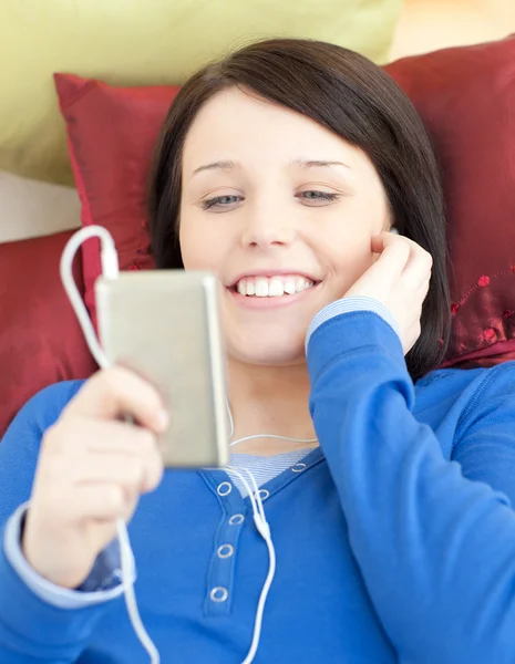 Ganska ung kvinna lyssnar musik liggande på en soffa — Stockfoto
