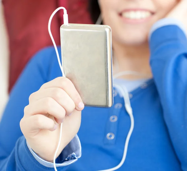 Close-up de uma jovem mulher ouvindo música deitada em um sofá — Fotografia de Stock
