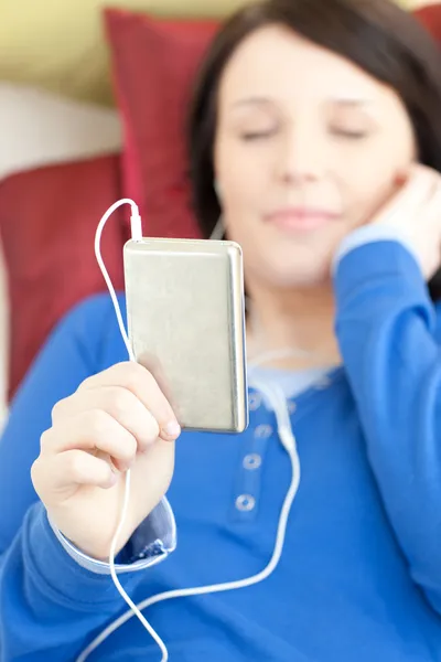躺在沙发上的白种人的年轻女人听音乐 — 图库照片