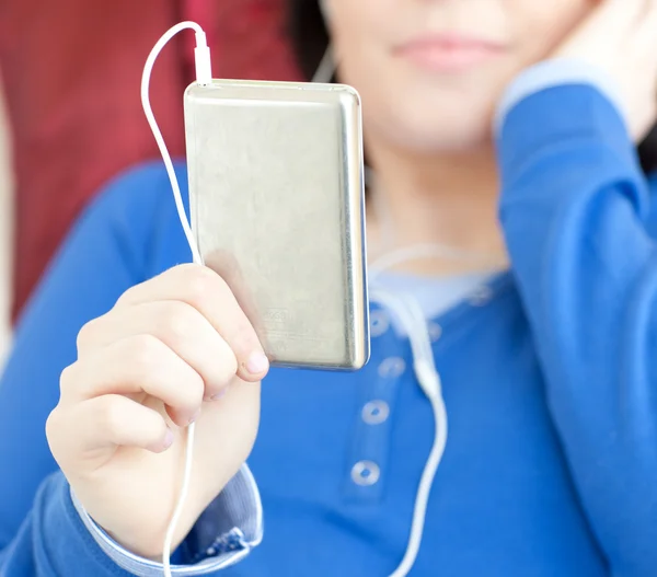 Close-up de uma menina adolescente morena ouvindo música deitada em um sofá — Fotografia de Stock