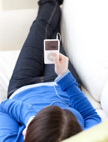 Close-Up sof üzerinde yatan bir beyaz genç kız müzik dinleme — Stok fotoğraf