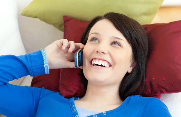 Счастливая девочка-подросток разговаривает по телефону, лежа на диване — стоковое фото