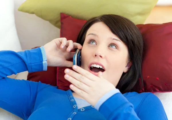 Sürpriz bir genç kız kanepede yatan telefonda konuşuyor — Stok fotoğraf