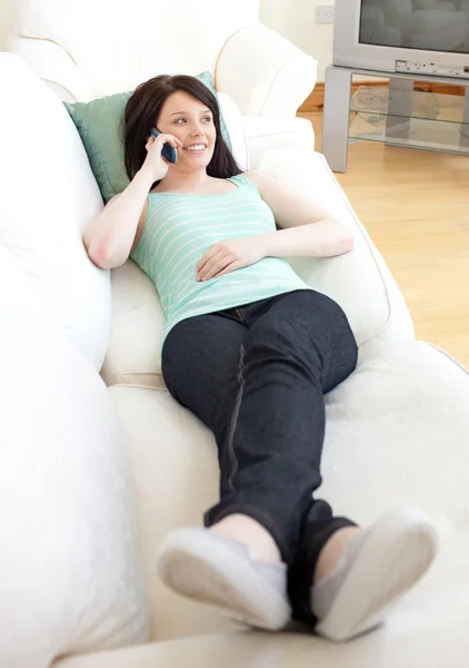 Очаровательная женщина разговаривает по телефону лежа на диване — стоковое фото