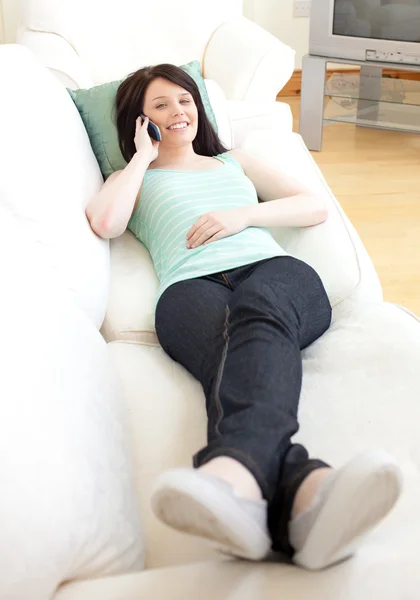 Улыбающаяся женщина разговаривает по телефону, лежа на диване — стоковое фото