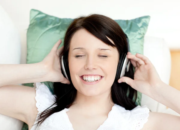 Весела дівчина-підліток слухає музику, що лежить на дивані — стокове фото