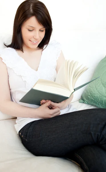 集中阅读一本书坐在沙发上的女人 — 图库照片