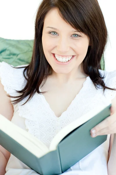 Donna brillante che legge un libro sdraiata su un divano — Foto Stock