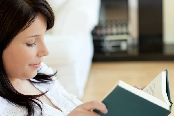 Серйозна жінка читає книгу, що лежить на дивані — стокове фото