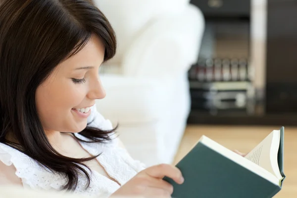 Donna attraente che legge un libro sdraiato su un divano — Foto Stock