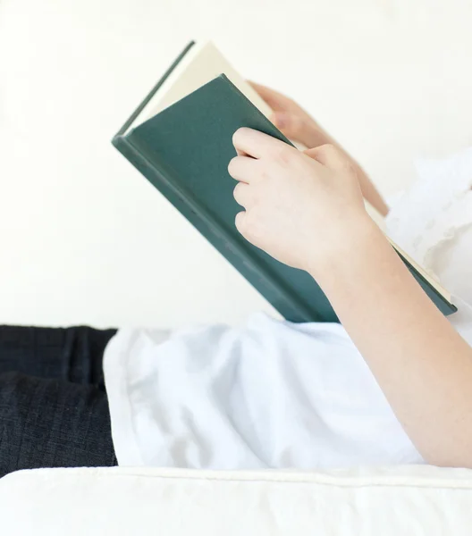Крупный план женщины, читающей книгу, лежащую на диване — стоковое фото