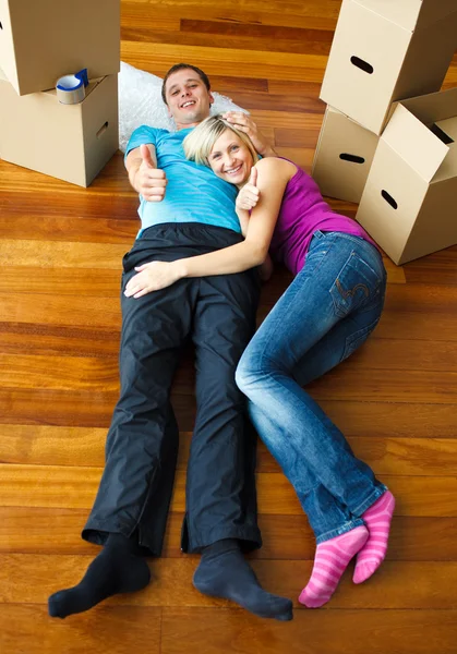 Paar liggend op de vloer met duimen omhoog. bewegende huis — Stockfoto