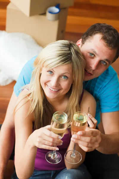 Új ház pezsgővel ünneplő szerelmesek — Stock Fotó