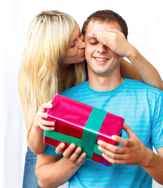 Женщина дарит подарок и целует мужчину — стоковое фото