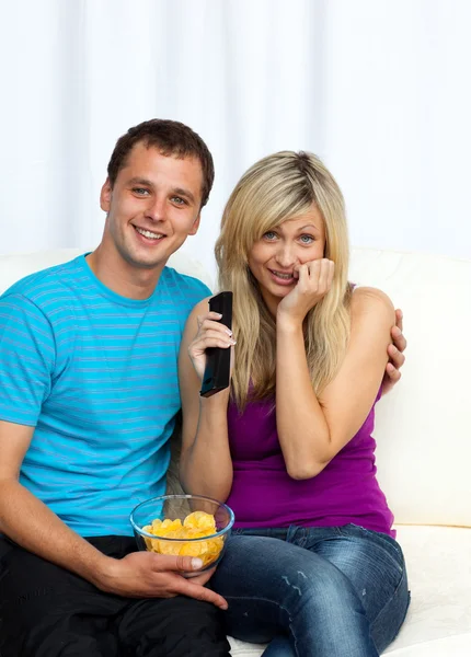 Casal assistindo um filme na televisão e comer batatas fritas — Fotografia de Stock