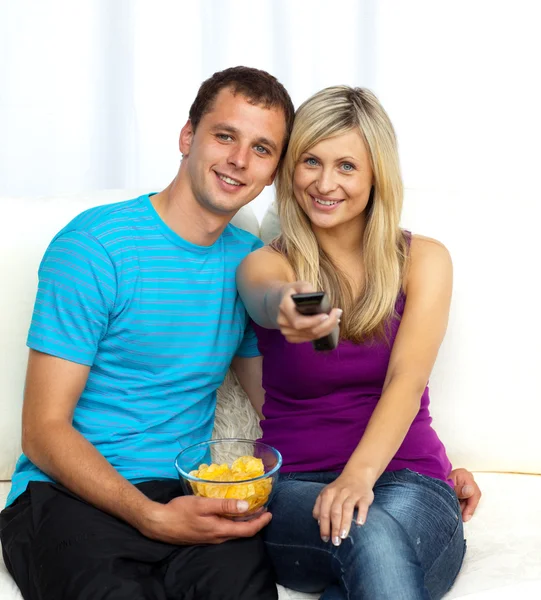 Feliz casal assistindo televisão e comer batatas fritas — Fotografia de Stock