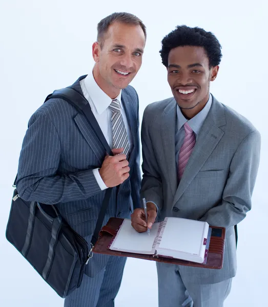 Uomini d'affari sorridenti che scrivono in un diario aziendale — Foto Stock