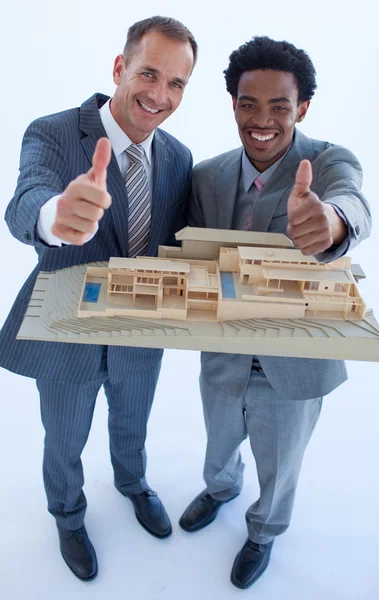 Αρχιτέκτονες, κρατώντας ένα σπίτι μοντέλο με τους αντίχειρες επάνω — Φωτογραφία Αρχείου