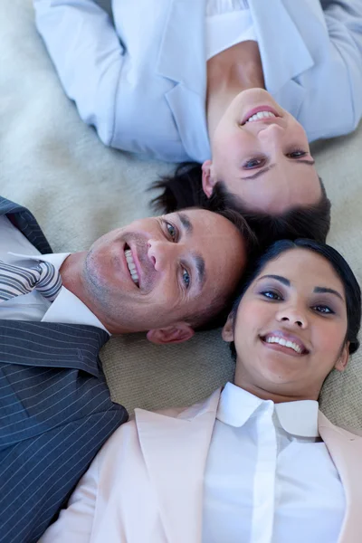 Business team on floor with heads together smiling — Stock Photo, Image