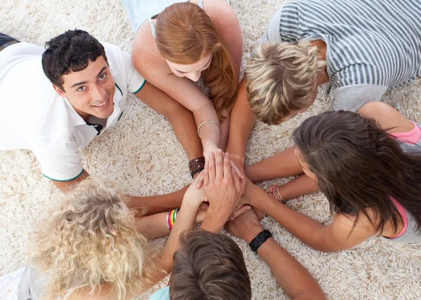 Teenagers lying on the ground with hands together — Stock Photo, Image