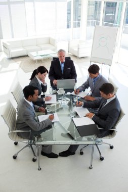 High angle of a senior manager in a meeting with his team clipart