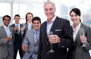 Smiling inernational business team holding glasses of Chamoagne clipart