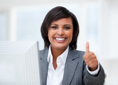 Happy businesswoman with a thumb up working at a computer clipart