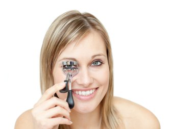 Smiling woman using an eyelash curler clipart