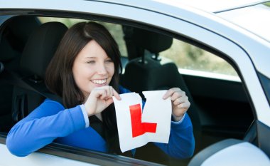 Joyful teen girl sitting in her car tearing a L-sign clipart