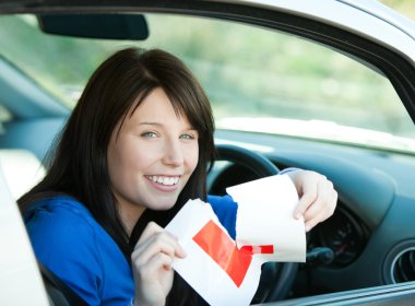 Charming brunette teen girl sitting in her car tearing a L-sign clipart