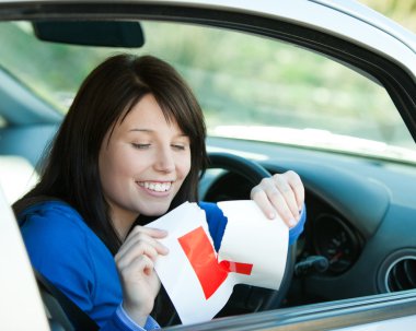 Brunette teen girl sitting in her car tearing a L-sign clipart